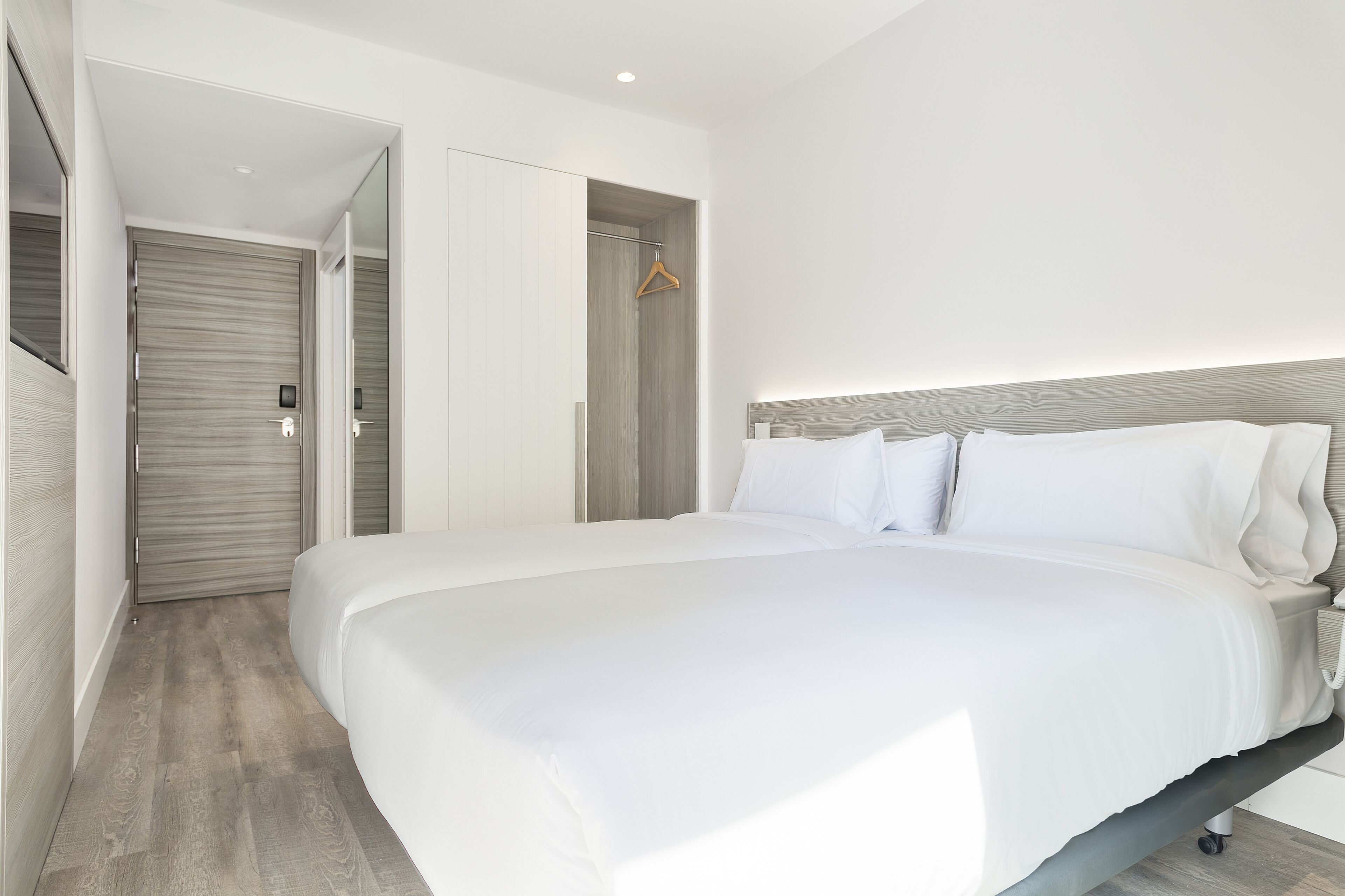 A modern hotel room with a large bed, a wardrobe, and a walk-in closet.