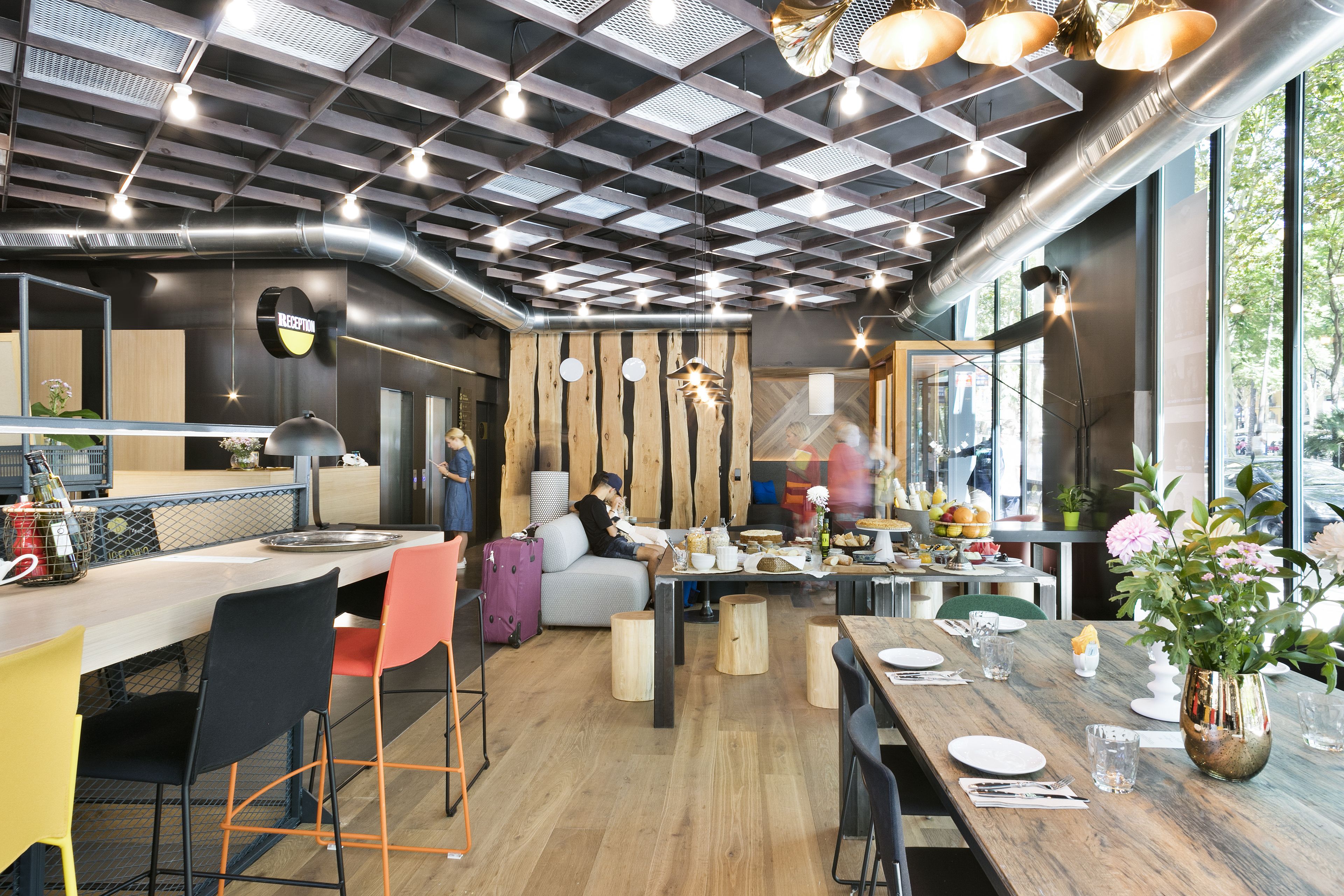 Un restaurante moderno con barra de madera, zona de estar y ventanas amplias.