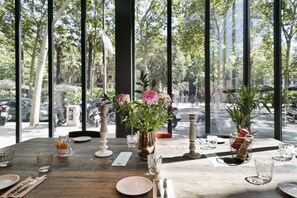 A dining table set with plates, cutlery, and glasses, with a vase of flowers and a potted plant on the table. - Hotel Niu Barcelona (Barcelona)