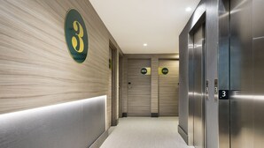 Un área de ascensores moderna con el número 3 en la pared, dos ascensores y un pasillo con piso de color claro.