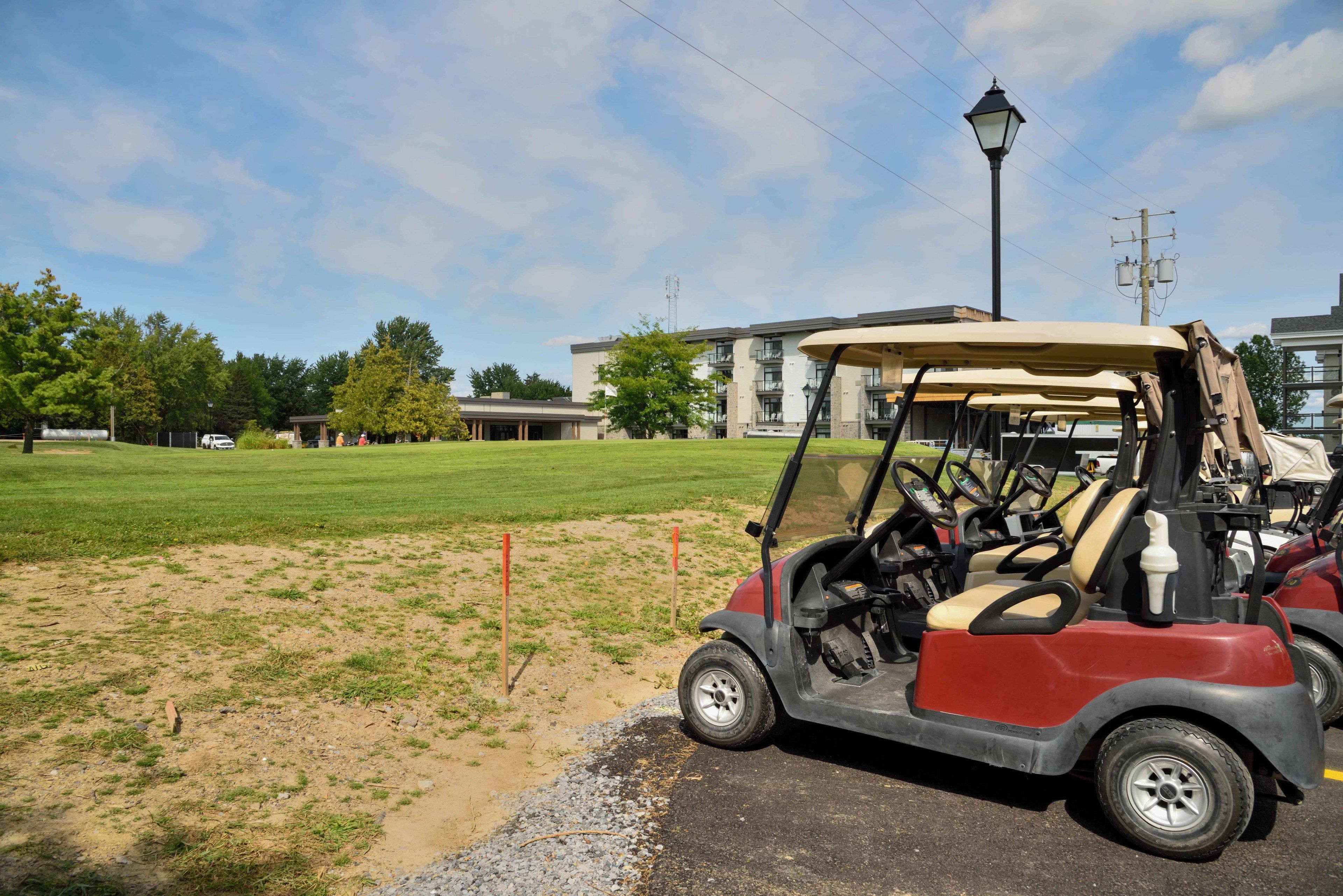 A golf cart parked on a sandy area with a building in the background.