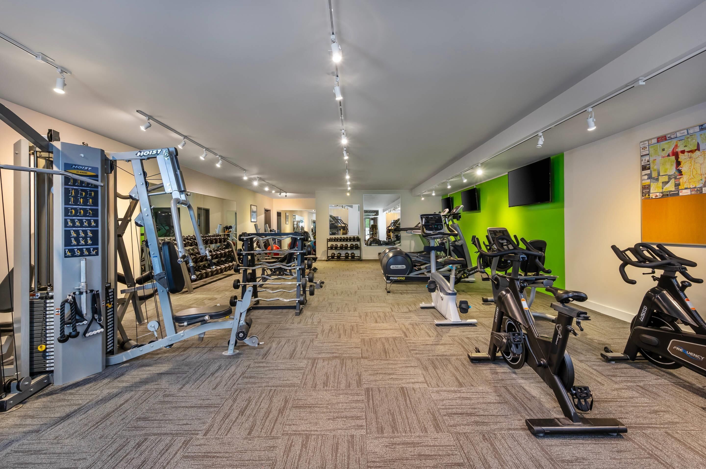 A gym with various exercise equipment, including weight machines, treadmills, and stationary bikes.