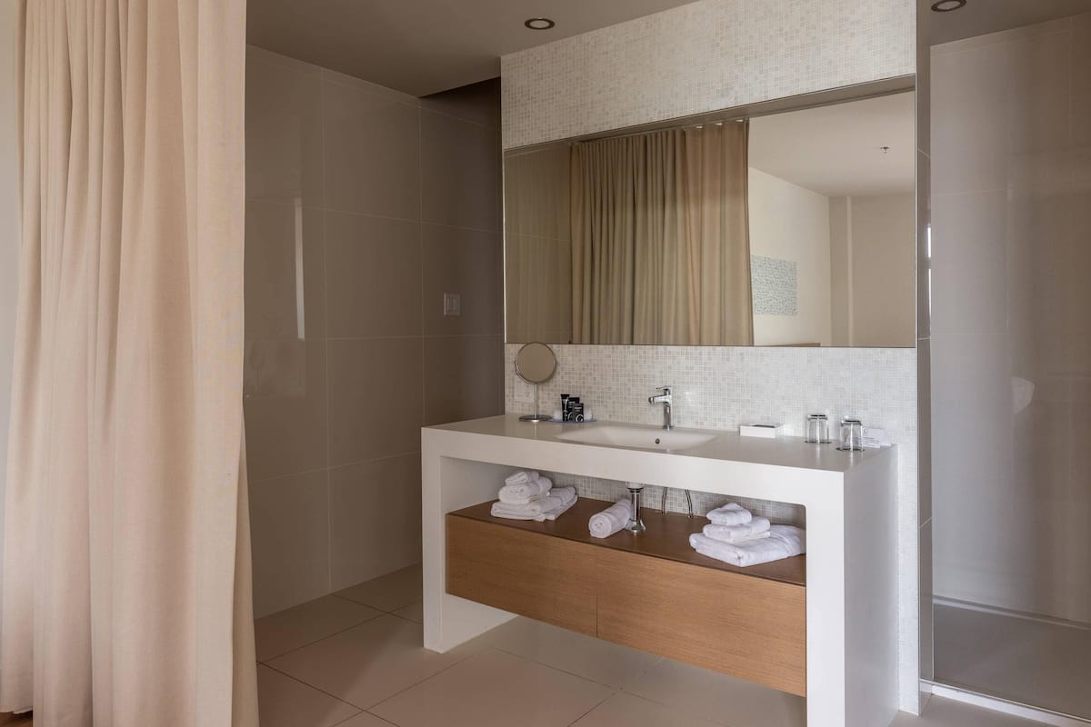 A modern bathroom with a white vanity, a mirror, and a shower area.