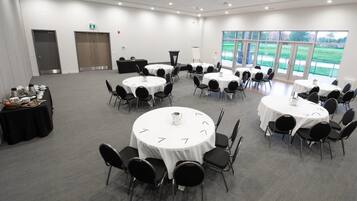 Une salle de conférence équipée de plusieurs tables rondes, de chaises et d’un buffet proposant des plats et des boissons.