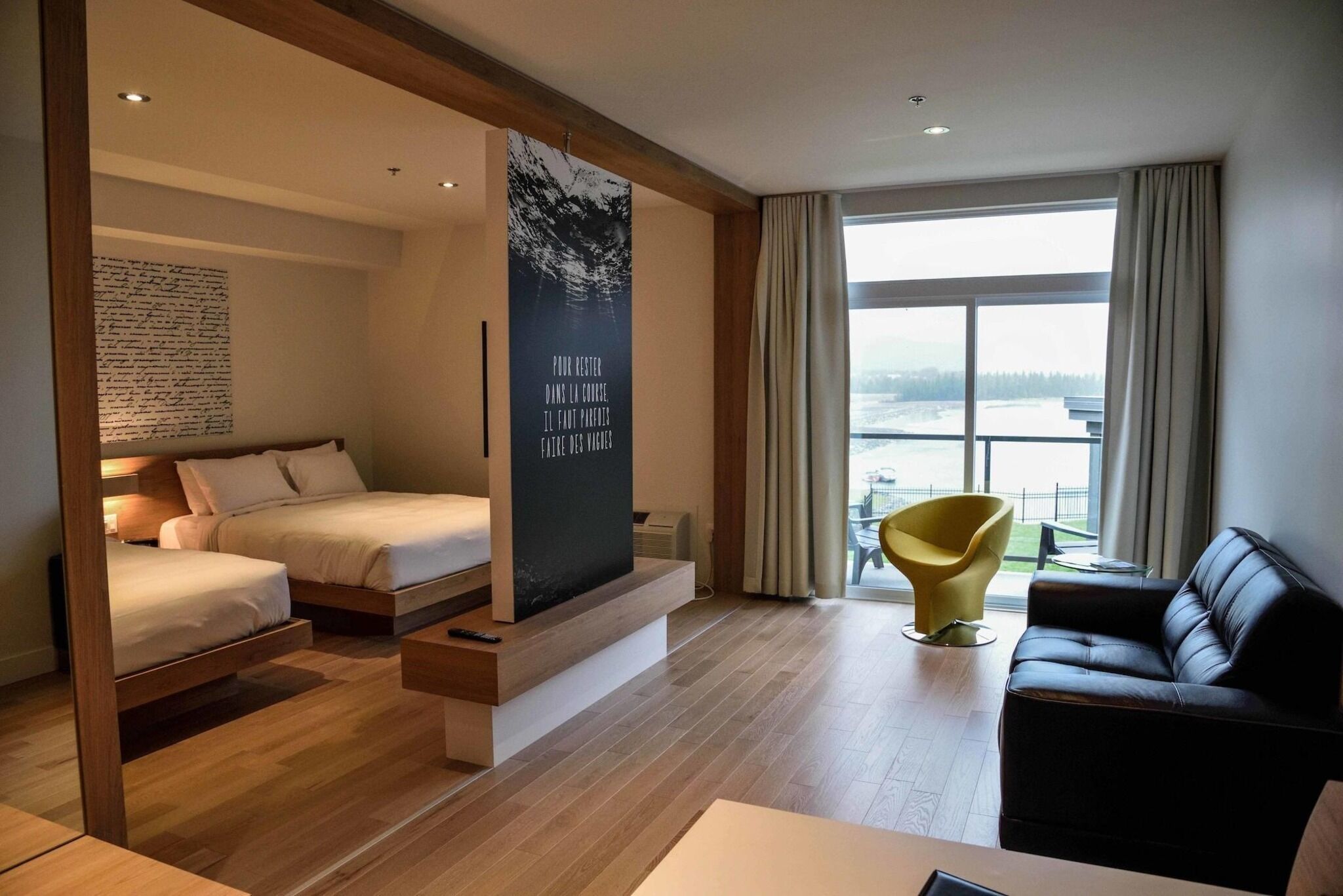 Ein modernes Hotelzimmer mit einem Bett, einer Couch, einem Sessel und einem großen Fenster mit Blick.