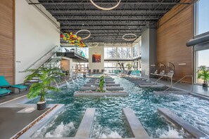 An indoor swimming pool with a modern design, featuring a central water feature and surrounding lounge areas. - Hotel du Lac Champlain, an Ascend Collection Hotel (Venise-en-Quebec)