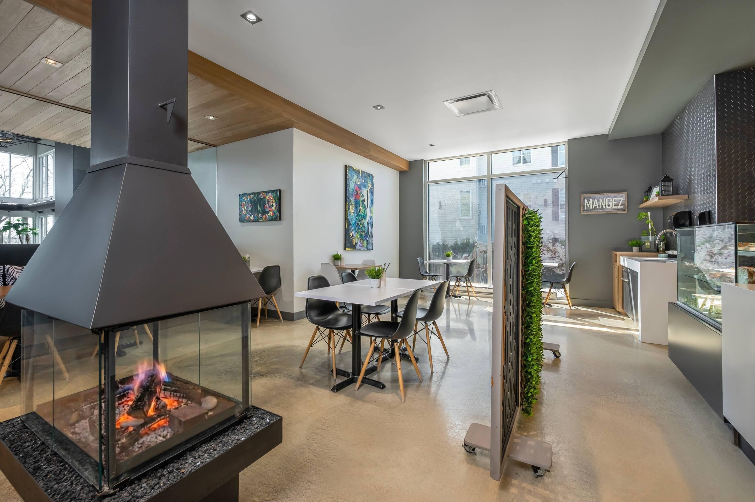 A modern kitchen with a glass enclosure, a dining area with a table and chairs, and a large window providing a view of the outside.