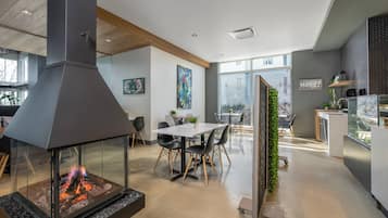 A modern kitchen with a glass enclosure, a dining area with a table and chairs, and a large window providing a view of the outside.