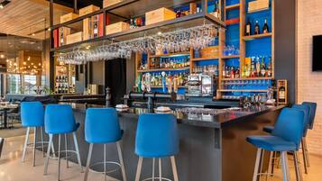 A bar area with a bar counter, stools, and shelves stocked with bottles.