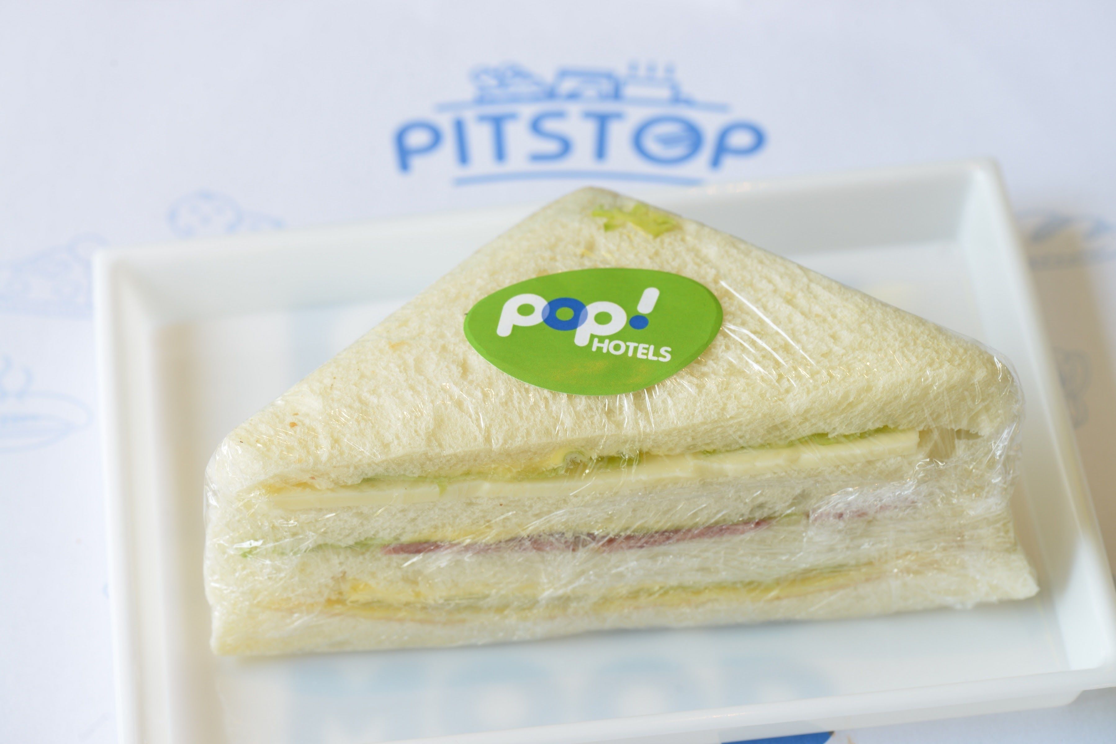 A sandwich with a 'Pop! Hotels' logo on a white plate.