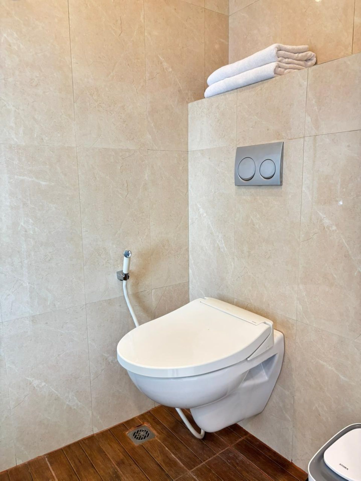 Un baño moderno con un inodoro blanco, un cabezal de ducha y un perchero.