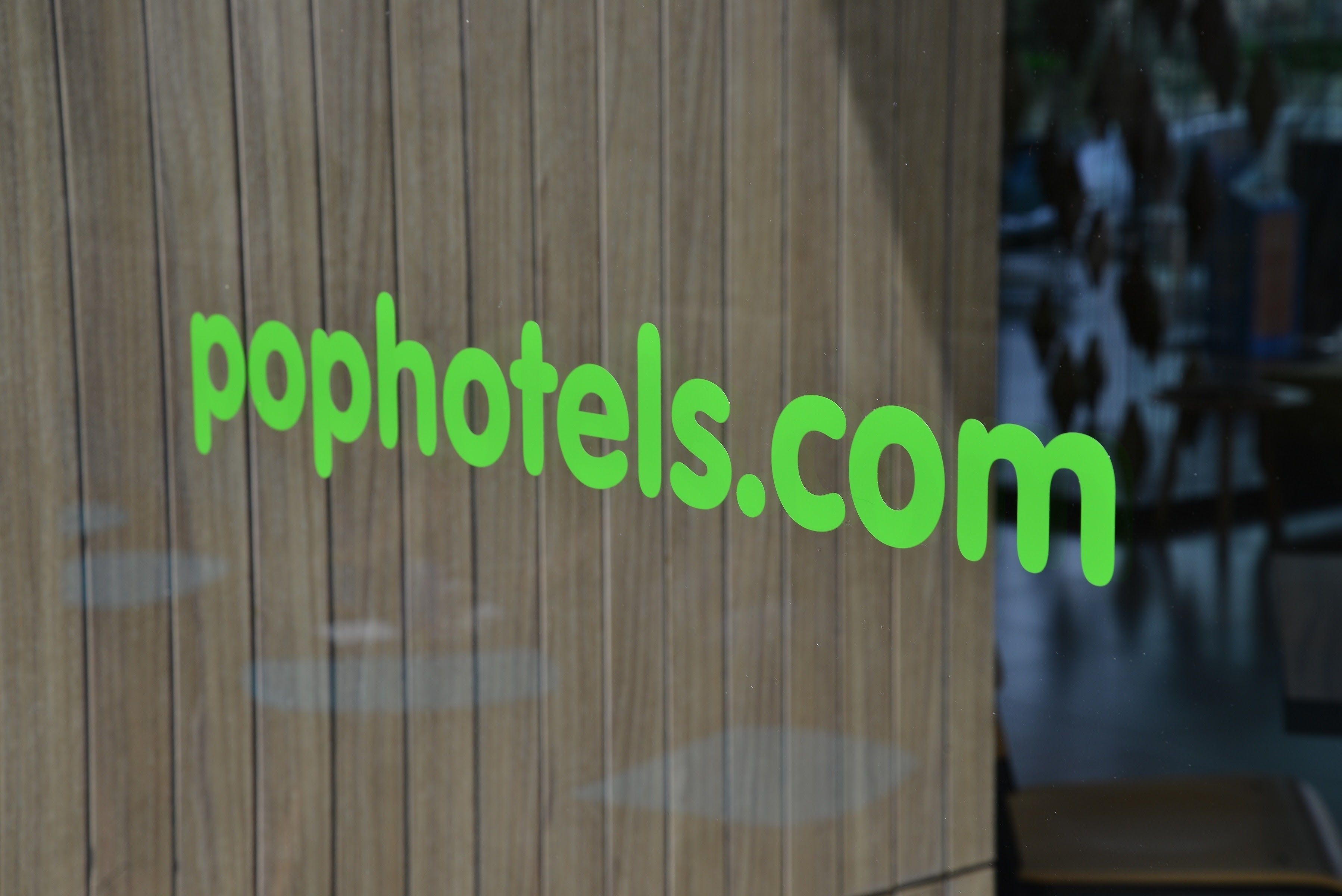 Una pared de madera con el texto 'pophotels.com' en verde.