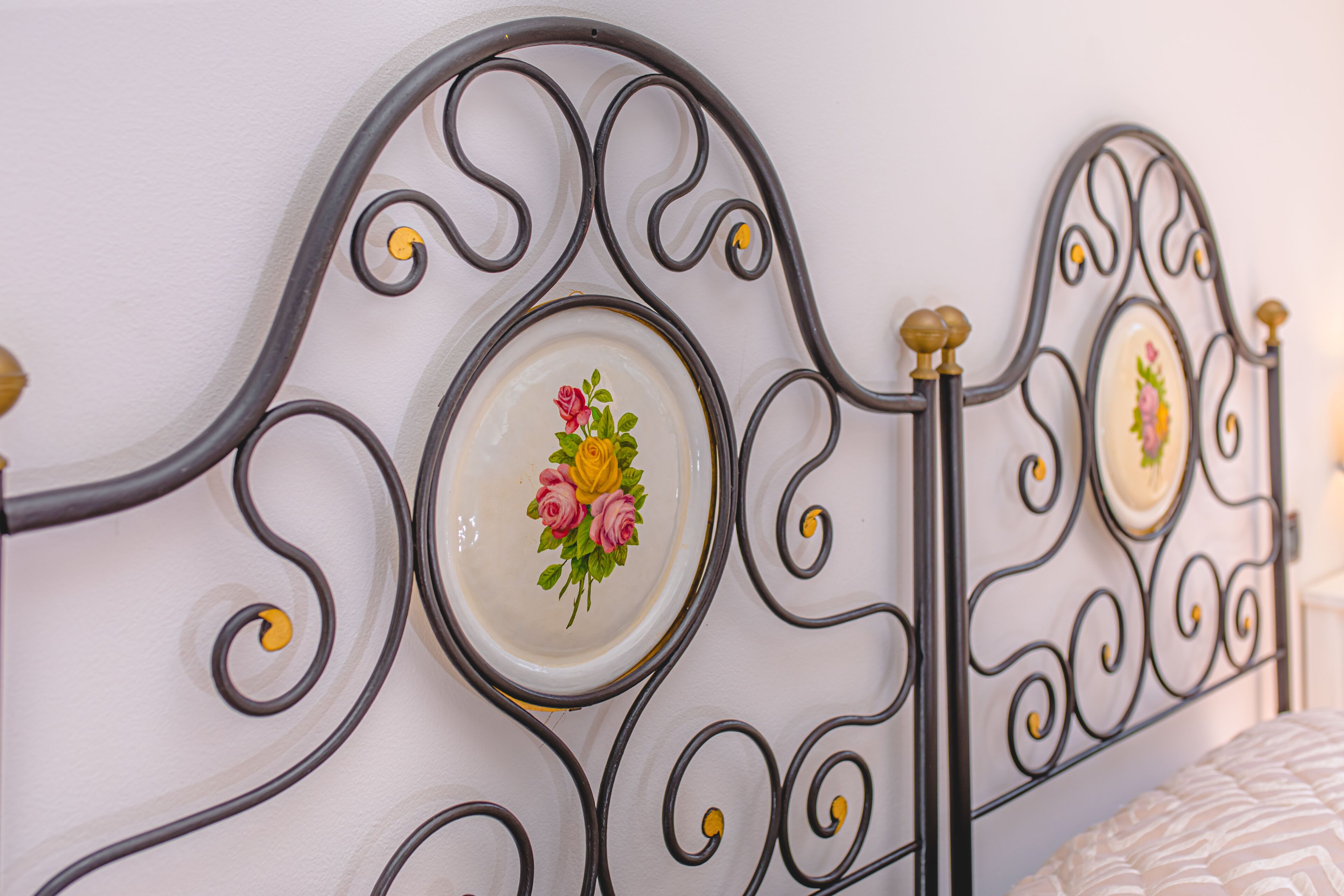 A metal bed frame with a decorative plate featuring a floral design.