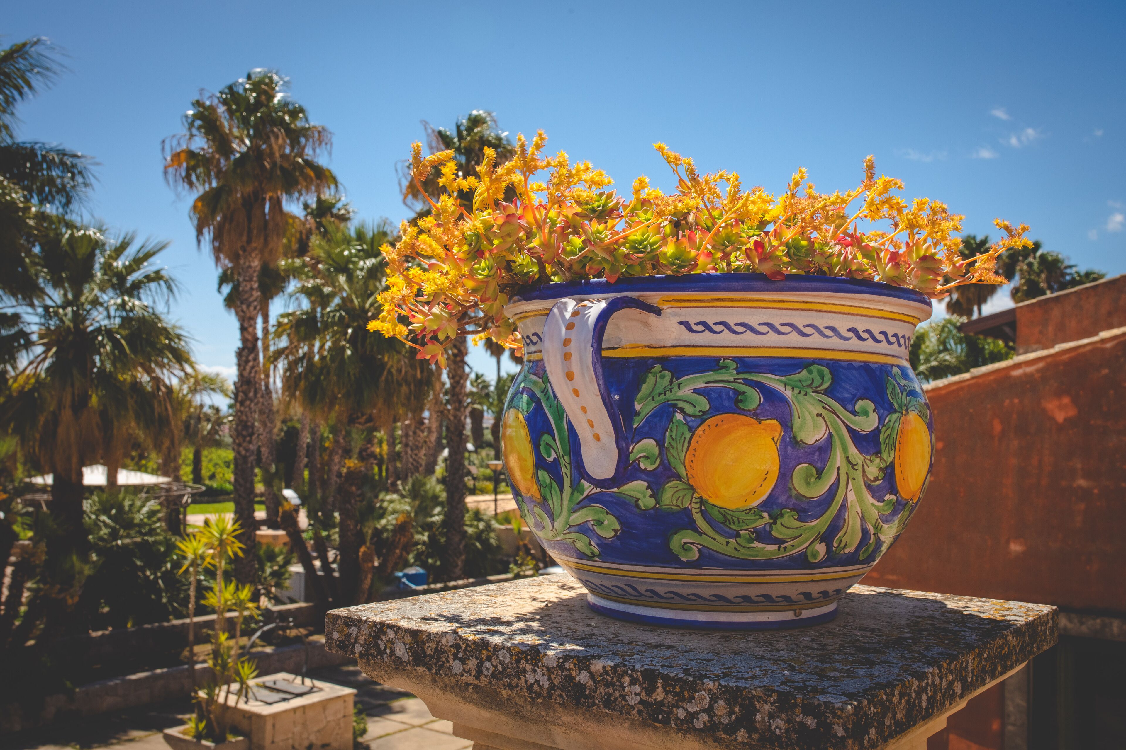 Un vaso di ceramica grande decorato con motivi floreali, appoggiato su una mensola di pietra.