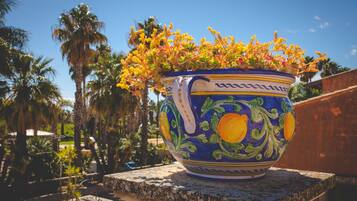 Un vaso di ceramica grande decorato con motivi floreali, appoggiato su una mensola di pietra.