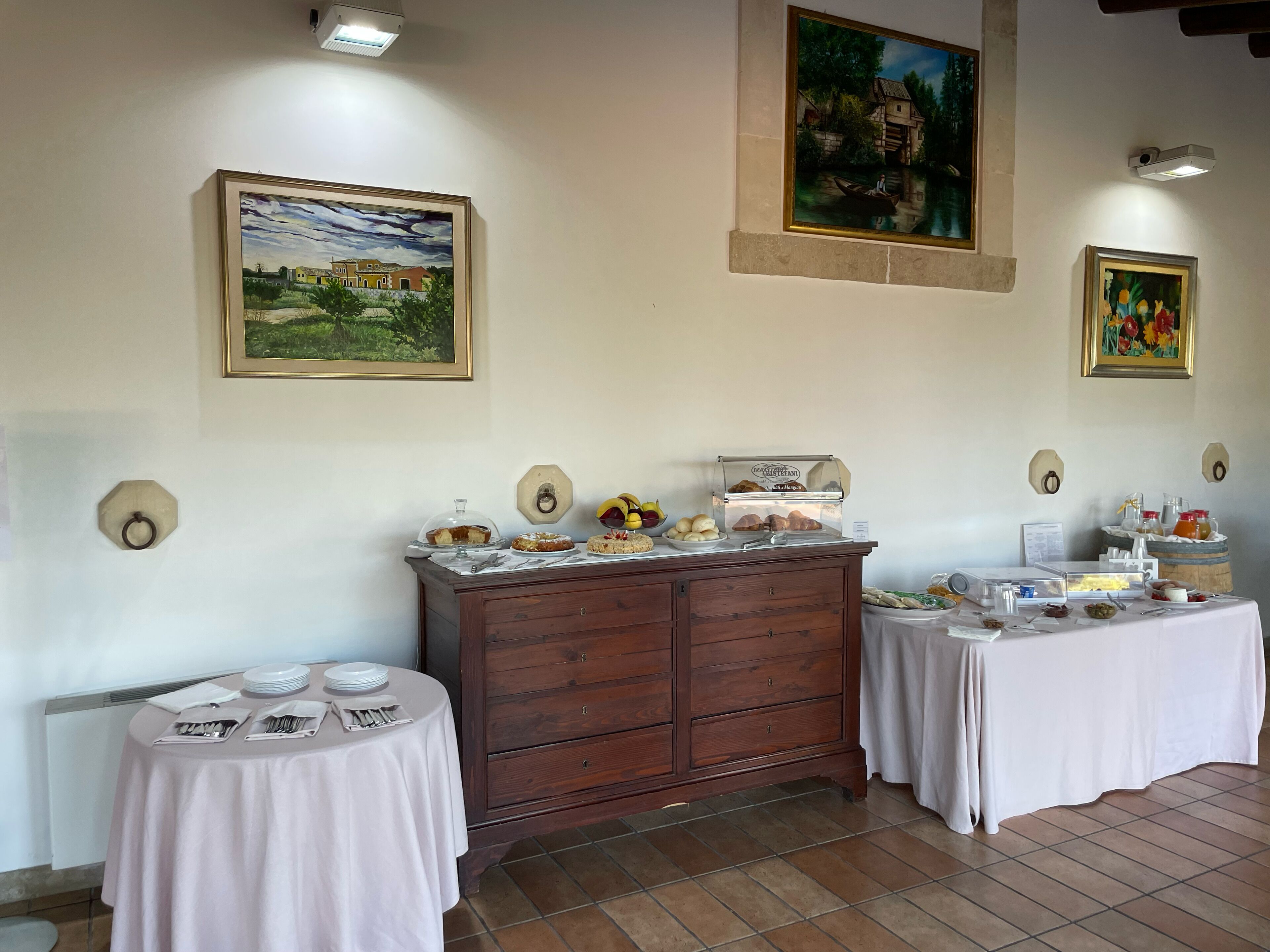 A dining area with a buffet setup, including a wooden cabinet and tables with white tablecloths.