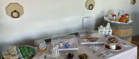 A buffet table with various food items and condiments, including cheese, fruits, and beverages.