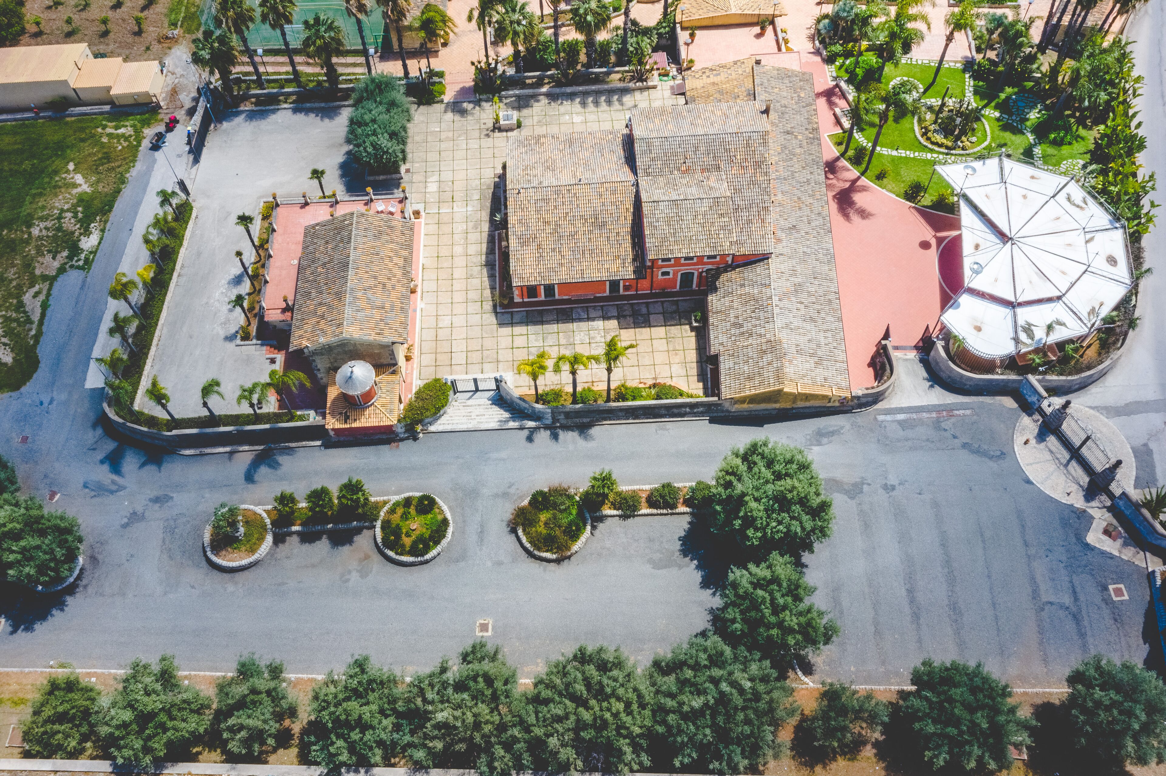 Vista aérea de una plaza con un edificio central, rodeado de árboles y una zona de estar circular.