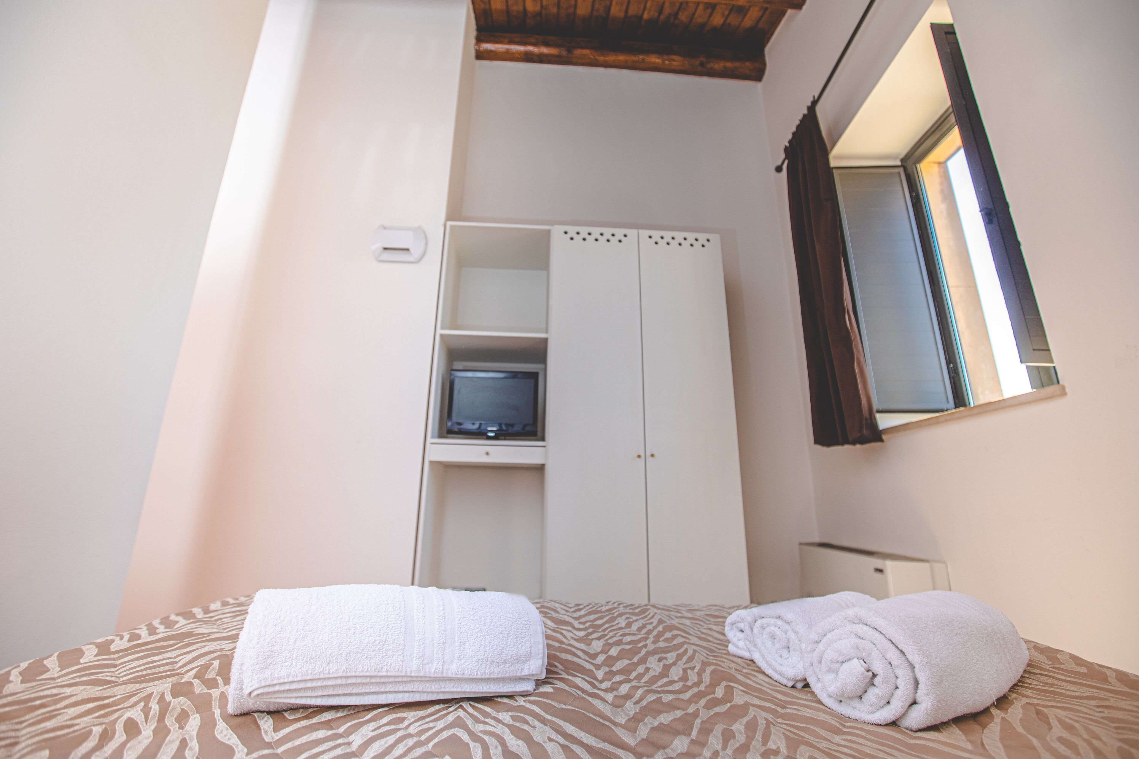 Un dormitorio con cama, armario, televisor y espejo.