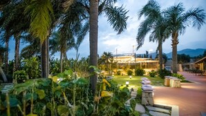 Un jardín ajardinado con palmeras y un edificio de fachada de vidrio.