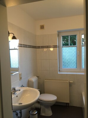 A small bathroom with a toilet, sink, and window.