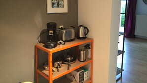 A kitchen with a coffee maker, toaster, kettle, and pots on a shelf. - Ferienwohnung Zacharias (Bad Hersfeld)