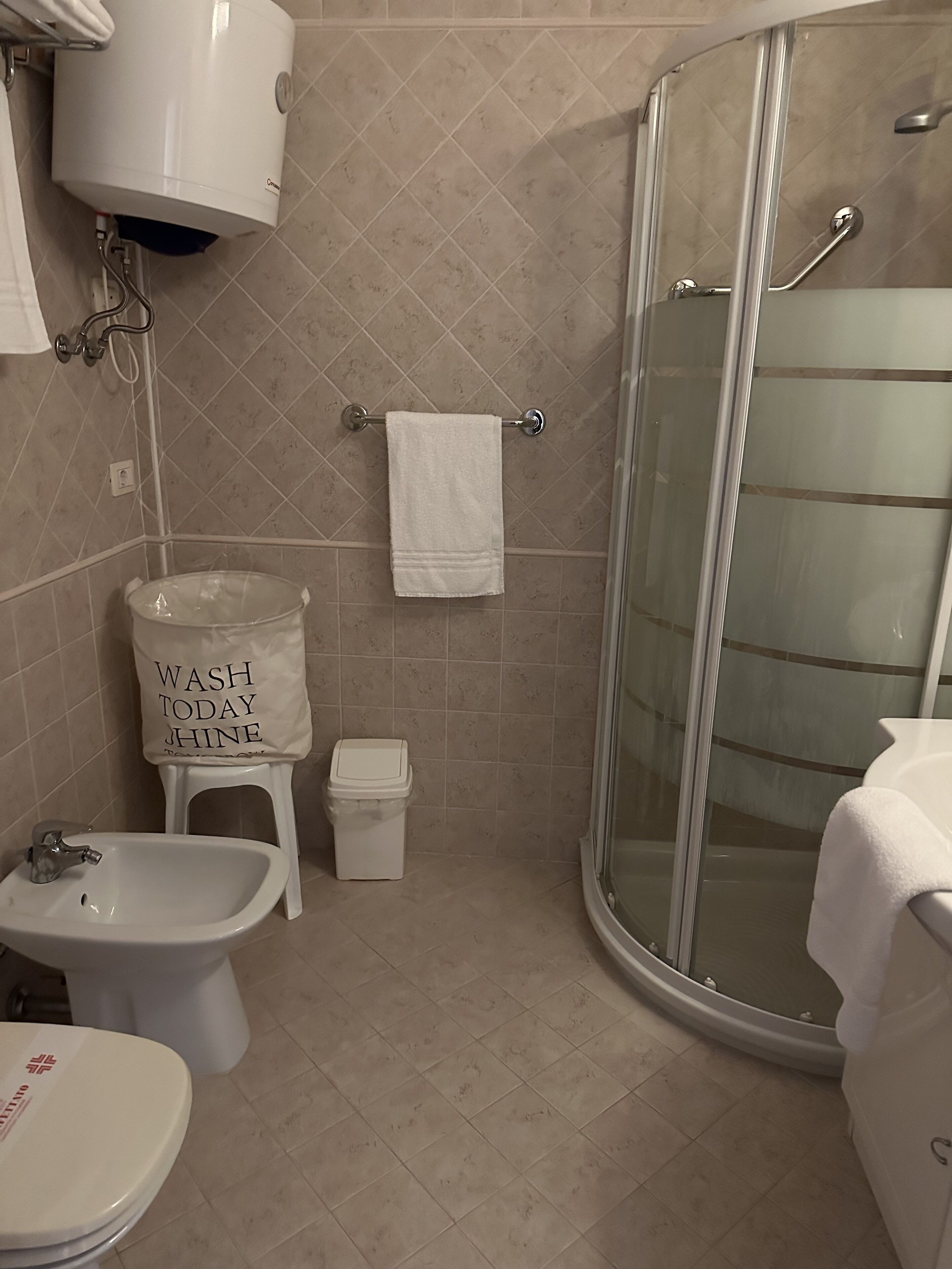 A bathroom with a toilet, bidet, and a glass-enclosed shower.