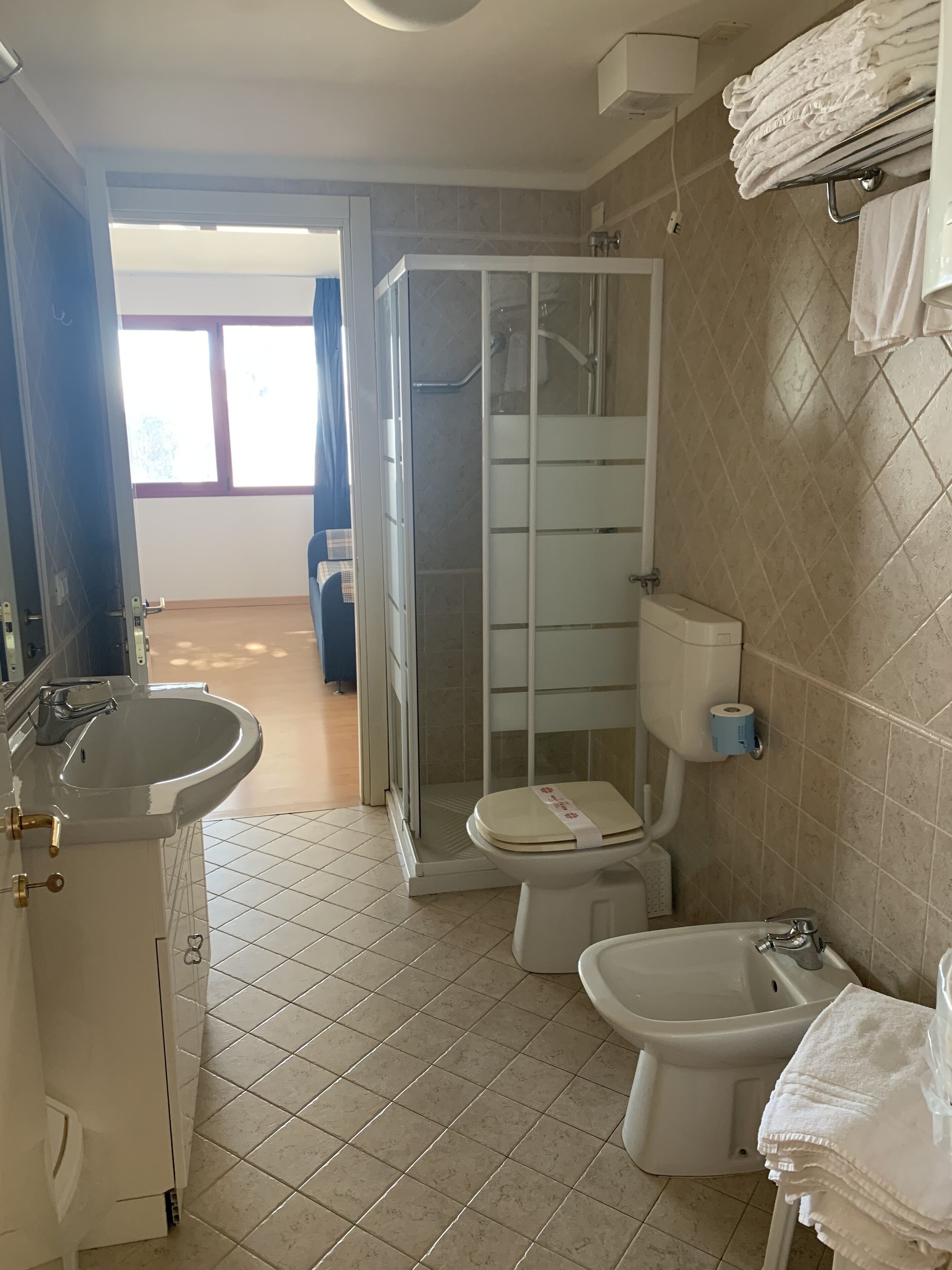 Un baño con ducha, inodoro, bidé, lavamanos y toallero.