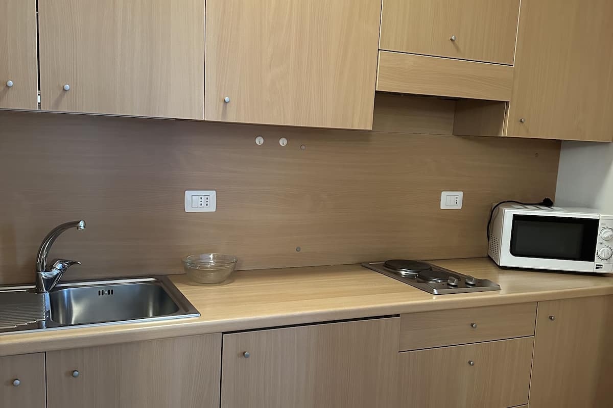 Une cuisine moderne avec des meubles en bois, un évier en acier inoxydable, un four à micro-ondes et un grille-pain.