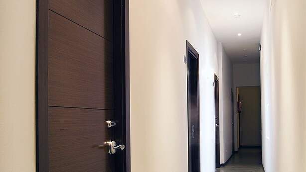 Un pasillo con una puerta de madera oscura marcada con el número 103, que da a una habitación.