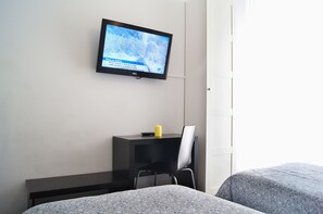 A hotel room with a bed, a desk with a chair, a TV mounted on the wall, and a window. - Hostal Cibeles (Madrid)