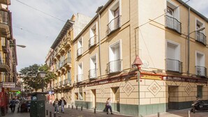 Un edificio de varios pisos con fachada color beige, múltiples balcones y entrada a nivel de calle.