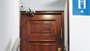 Una puerta de madera con un picaporte metálico y un felpudo rojo.
