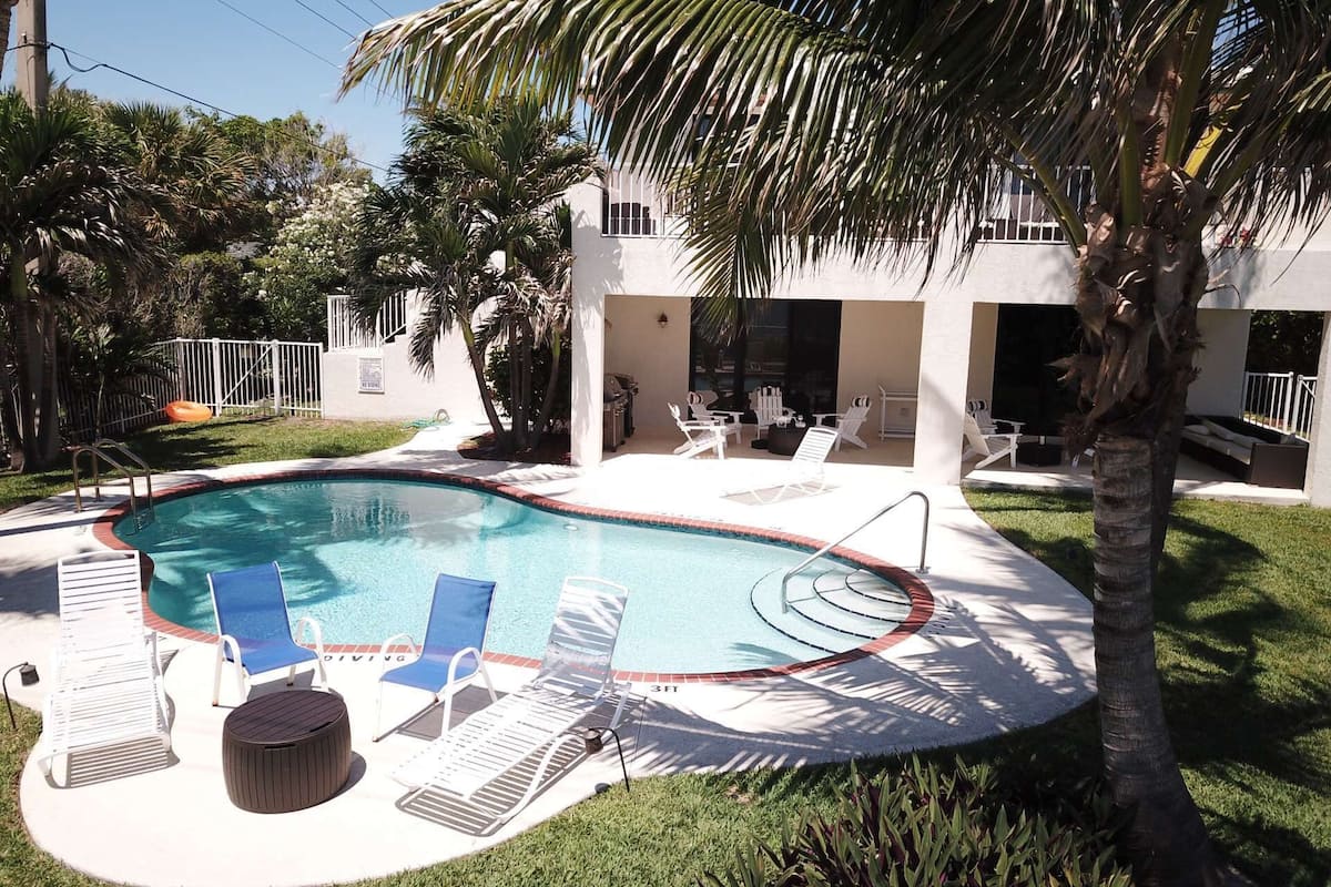 Una piscina con sillones de descanso y zona de barbacoa.