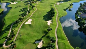A golf course with sand bunkers, water hazards, and palm trees. - Southwind by iTrip Palm Beach (Singer Island)