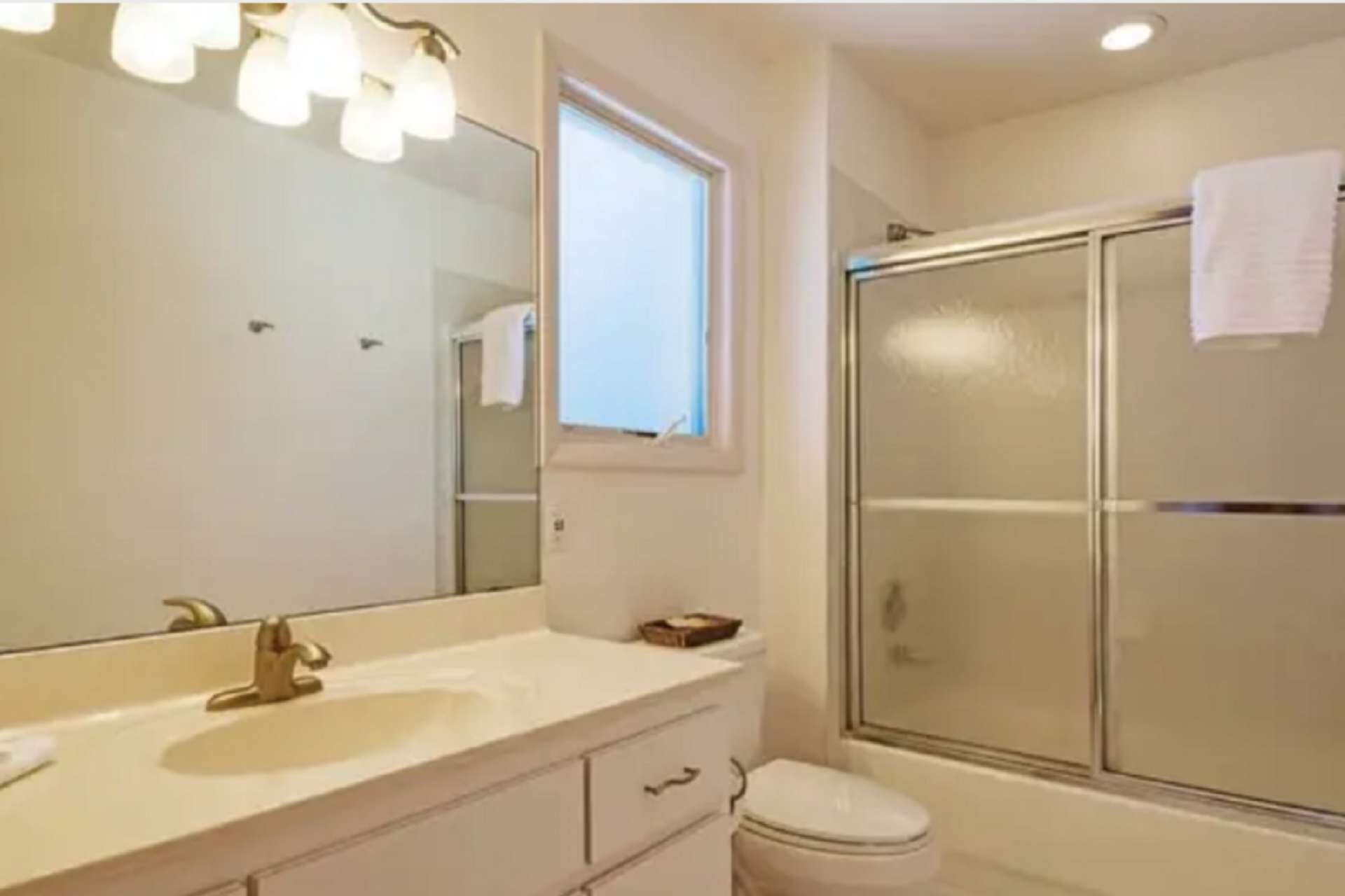 A bathroom with a sink, mirror, and a glass-enclosed shower.
