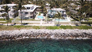 A coastal property with a swimming pool, multiple buildings, and a rocky shoreline. - Southwind by iTrip Palm Beach (Singer Island)