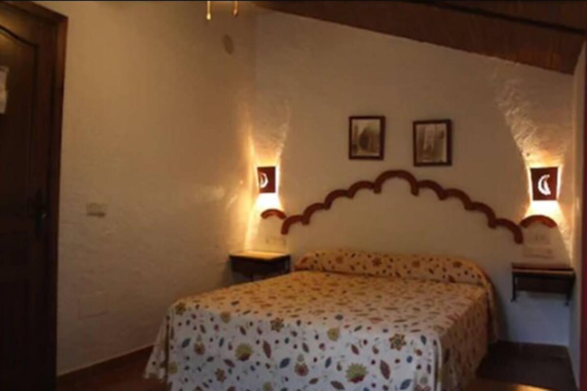 A bedroom with a bed, two bedside tables, and wall-mounted lamps.