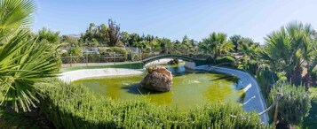 Un jardín ajardinado con un estanque, un puente y abundante vegetación.