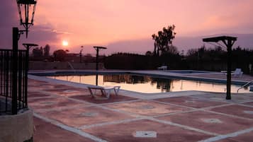 Una piscina al aire libre, sombrillas, sillones reclinables de piscina