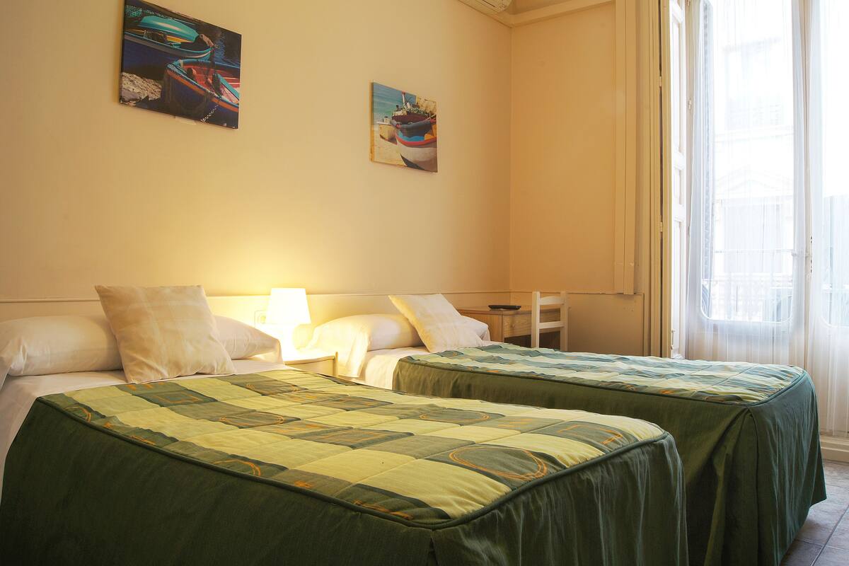 Une chambre d’hôtel avec deux lits, une table de chevet et deux tableaux au mur.