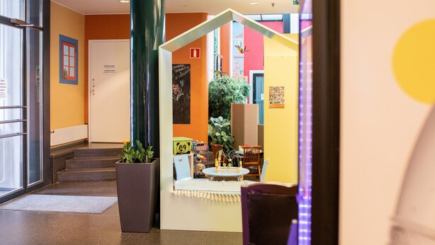 Um saguão de hotel com escada, balcão de recepção e área de recreação infantil.