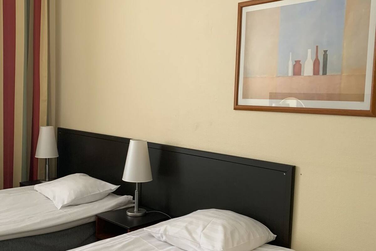 Une chambre d’hôtel avec deux lits, une table de chevet avec une lampe et un tableau encadré au mur.
