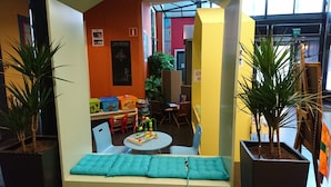 Espaço infantil com brinquedos coloridos, uma mesa pequena e cadeiras.