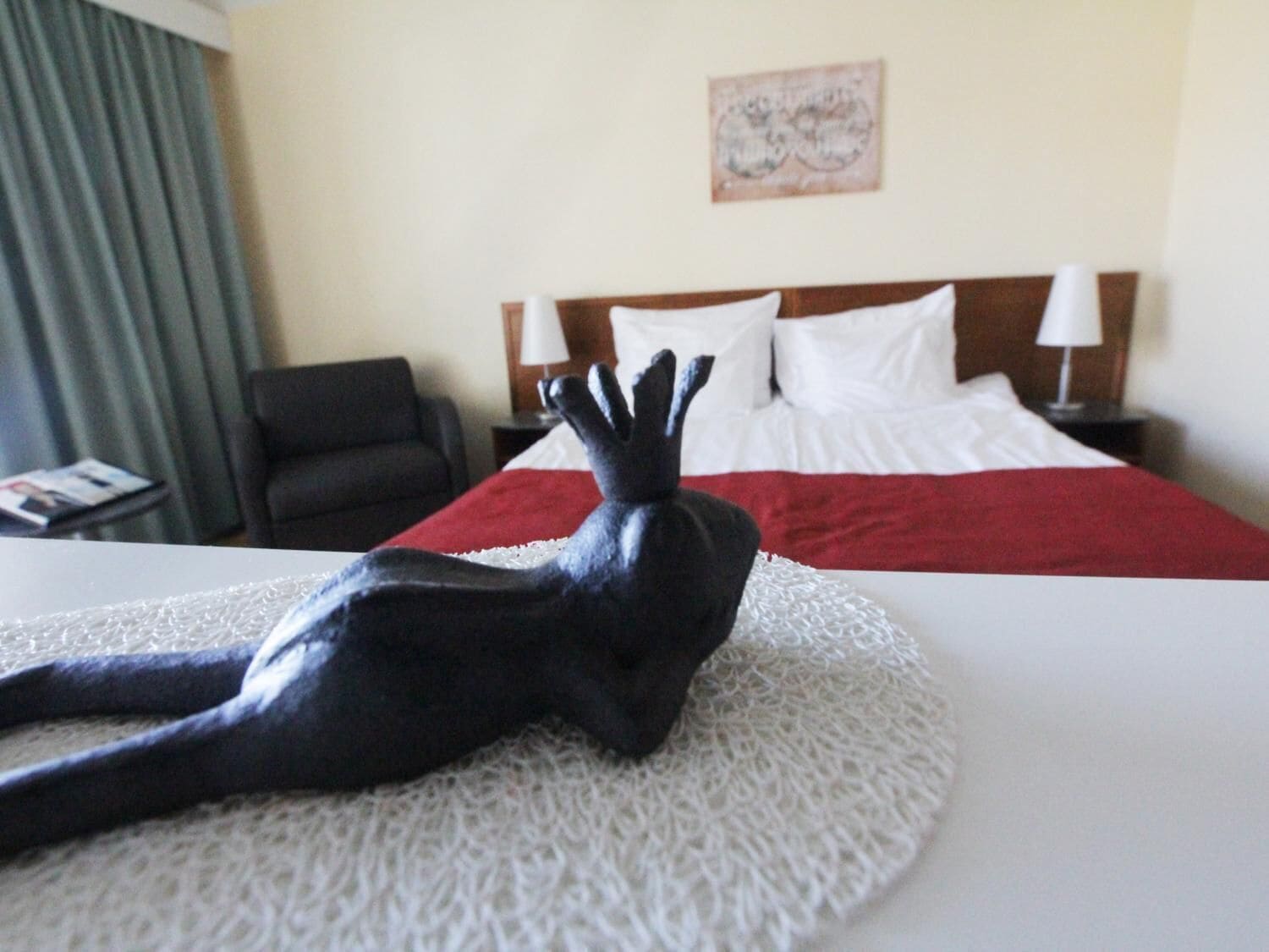 Ein Hotelzimmer mit Bett, Sessel, Nachttisch und einer dekorativen Skulptur.