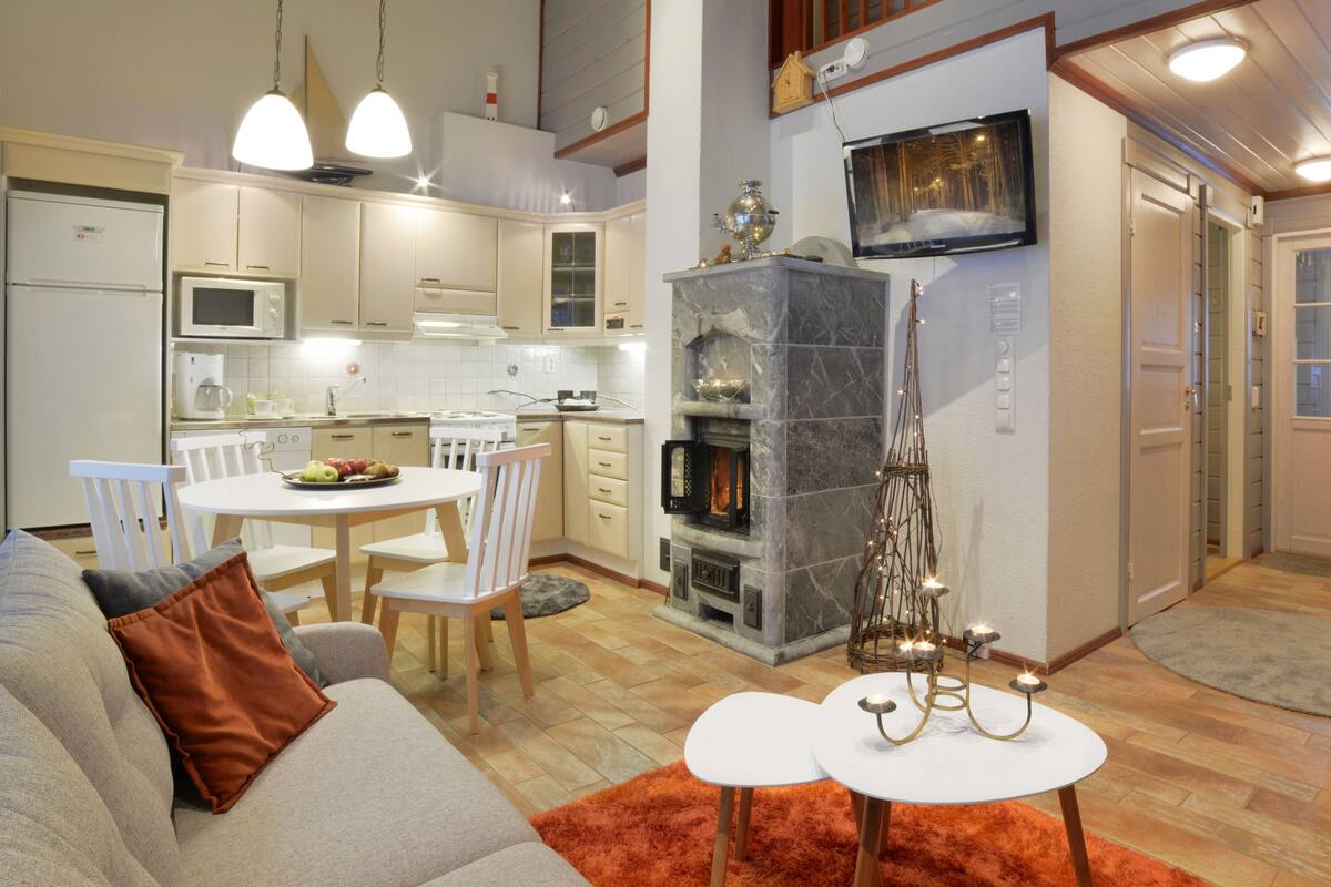 Una cocina moderna con armarios blancos, microondas y comedor con mesa y sillas blancas.