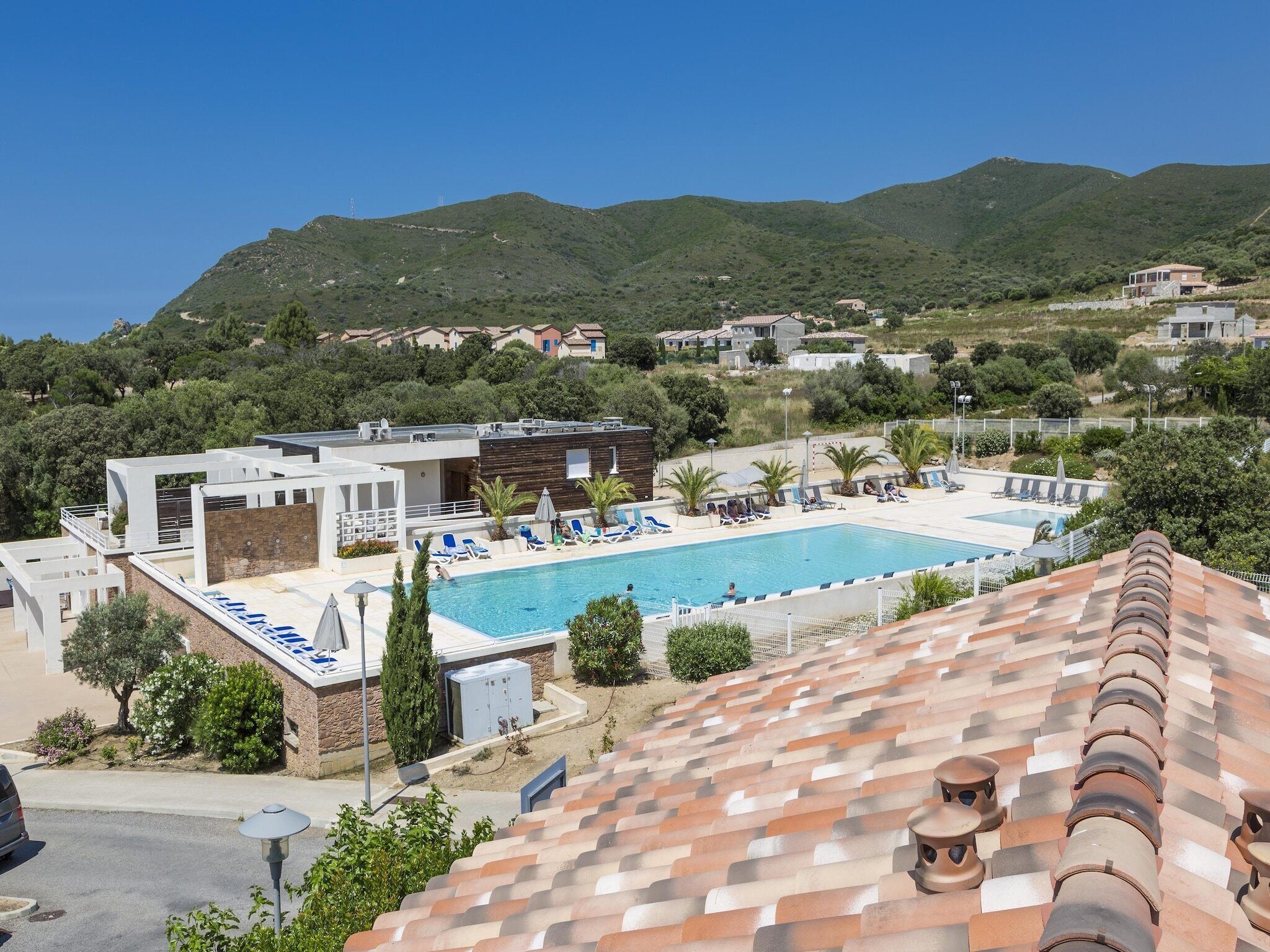 A pool area with a view of the surrounding landscape, including hills and buildings.