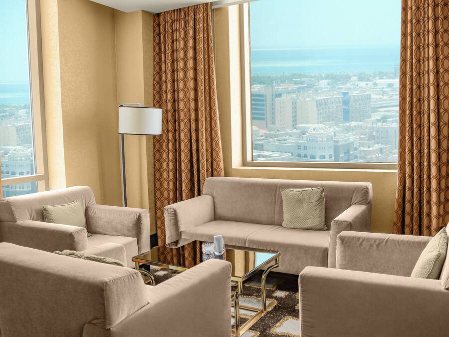 A modern living room with a sofa set, a coffee table, and a floor lamp. A large window offers a view of the cityscape.