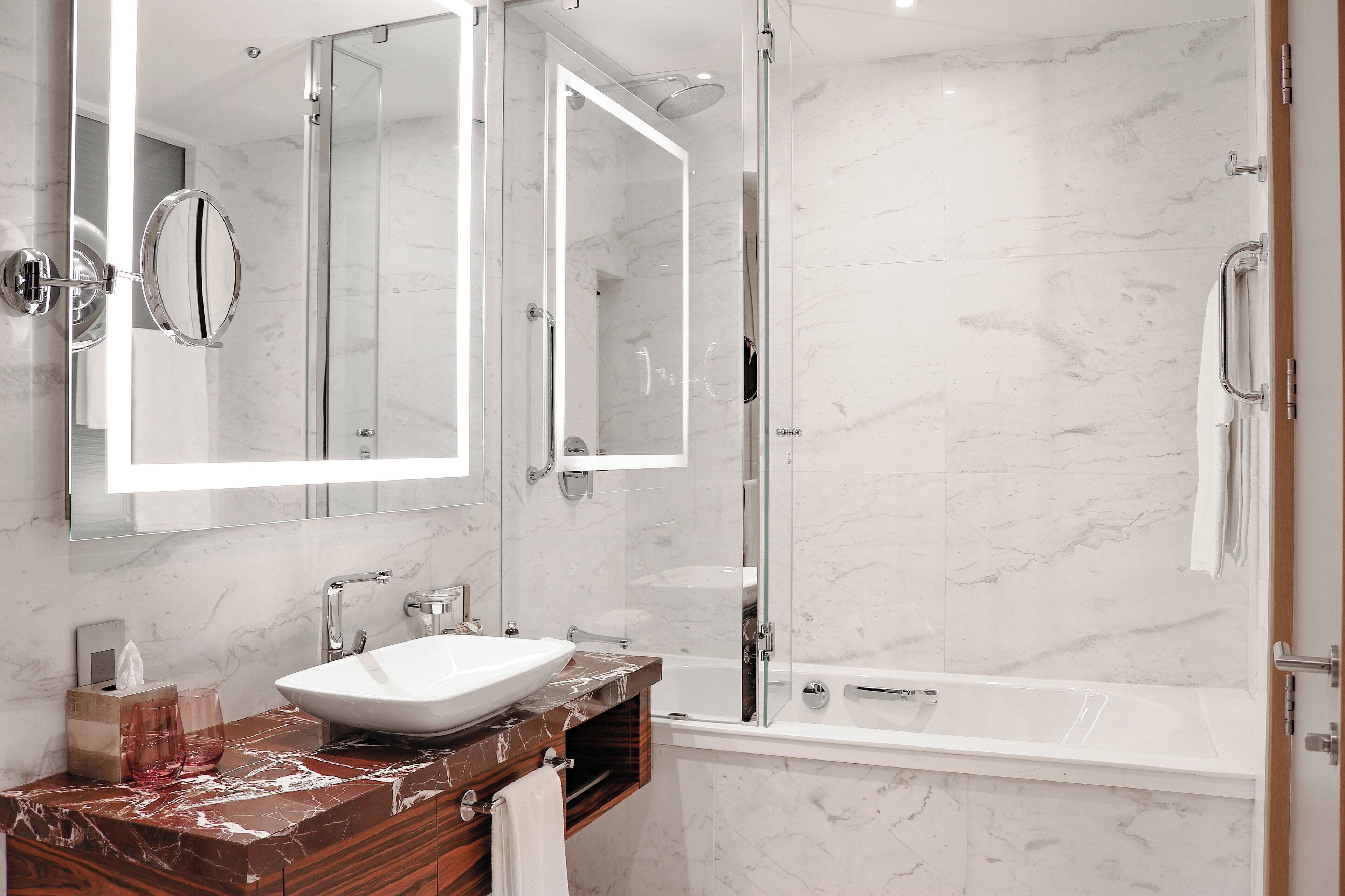 Une salle de bain moderne avec un lavabo en marbre, une douche à parois de verre et un grand miroir.
