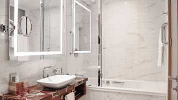 Un baño moderno con lavamanos de mármol, ducha con cerramiento de vidrio y un espejo grande.